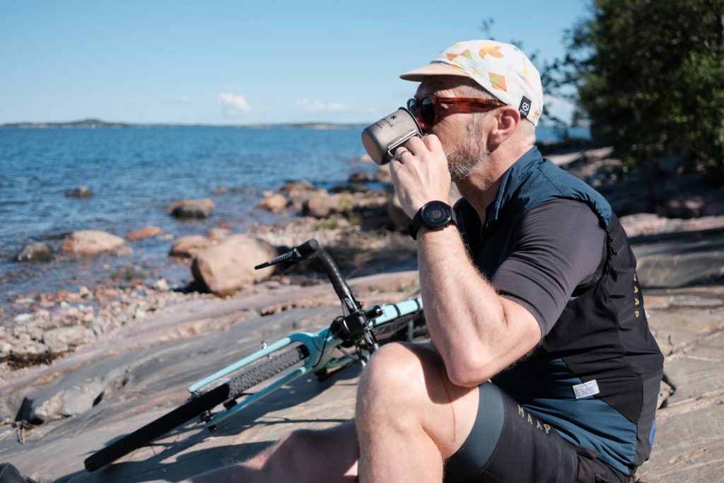 Pyöräilijä nauttii kahvia merenrannalla.